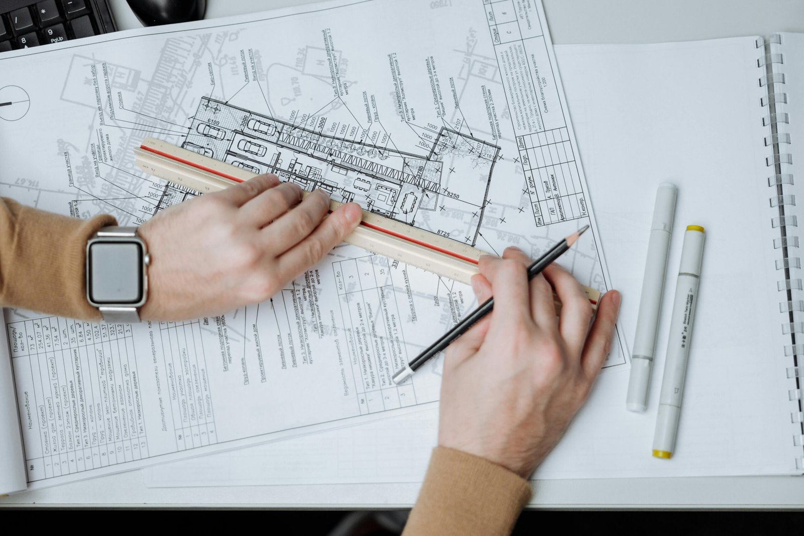 Hands sketching a floor plan with a ruler and pencil